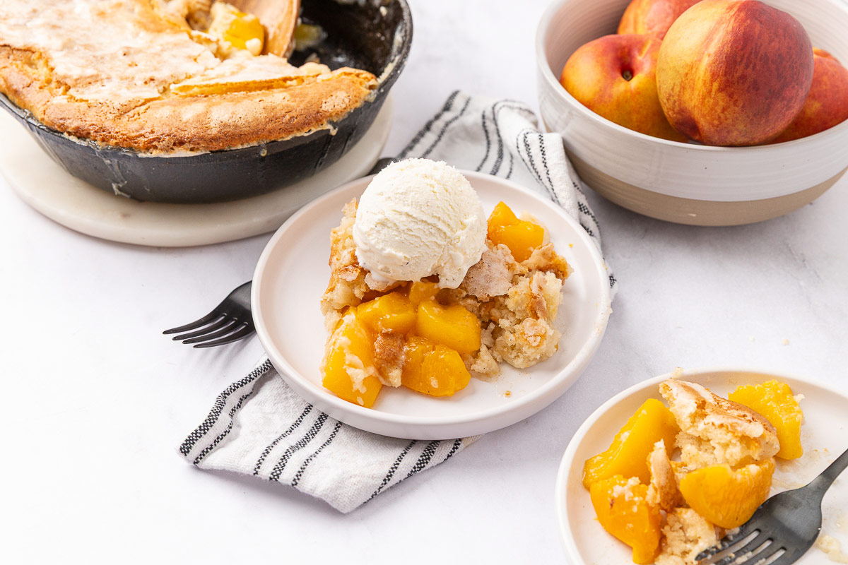 Το Peach Cobbler σερβίρεται σε ένα πιάτο με παγωτό βανίλιας στην κορυφή.